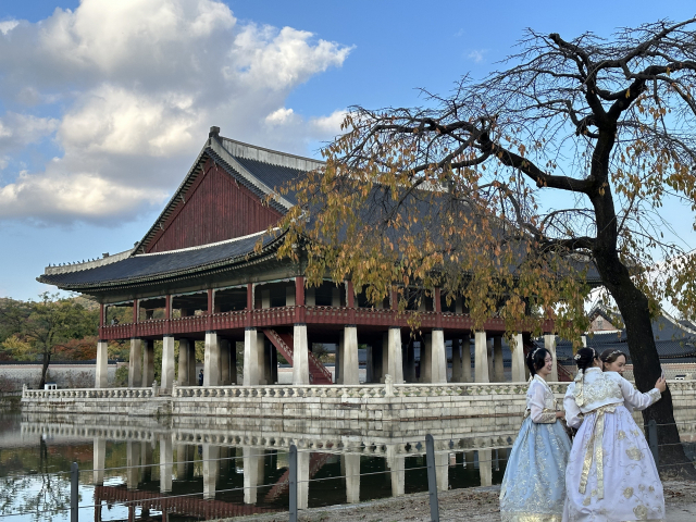 한복을 곱게 차려입은 관광객들이 경복궁 경회루를 배경으로 기념 촬영을 하고 있다.
