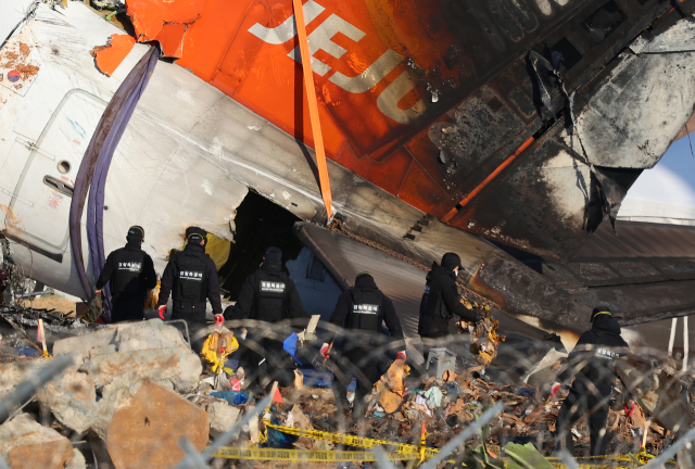 제주항공 여객기 참사 7일째인 4일 오후 무안국제공항 사고 현장에서 마무리 수색 작업을 하던 경찰특공대원들이 구명 조끼를 들고 현장을 나서고 있다. 연합뉴스