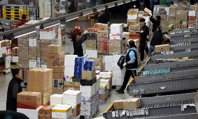 부산시는 부산지방우정청과 업무협약을 맺고 부산 외국인 유학생이 해외로 특급우편을 보낼 때 할인하는 혜택을 준다. 사진은 지난해 2월 설 명절을 앞두고 부산 강서구 부산우편집중국에서 직원들이 밀려드는 소포와 택배 물량을 분류하기 위해 분주하게 움직이는 모습. 부산일보DB