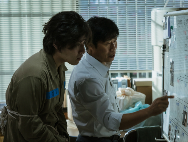 영화 ‘야당’에서 억울하게 옥살이를 하게 된 이강수(강하늘·왼쪽)가 구관희 검사(유해진·오른쪽)에게 마약 사범 정보를 캐낼 작전을 듣고 있는 모습. 플러스엠 엔터테인먼트, 하이브미디어코프 제공