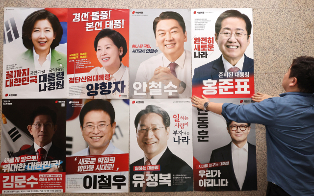 20일 서울 여의도 국회 본청 국민의힘 사무실 앞에 당 관계자가 대선 경선 후보자 포스터를 붙이고 있다. 연합뉴스