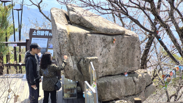 한 가족이 팔공산 소원바위에 동전을 붙이면서 소원을 빌고 있다. 남태우 기자