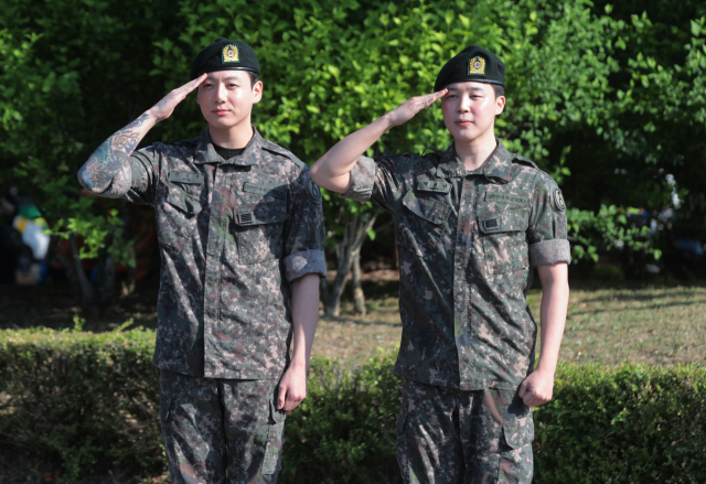 육군 현역 복무를 마치고 만기 전역한 그룹 방탄소년단(BTS)의 지민(오른쪽)과 정국이 지난 11일 경기도 연천군 연천공설운동장에서 취재진과 팬들을 향해 거수 경례하고 있다. 연합뉴스