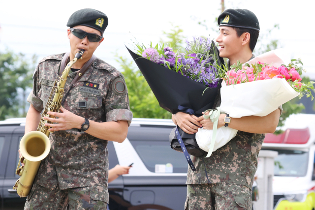 육군 현역 복무를 마치고 만기 전역한 그룹 방탄소년단(BTS) RM이 지난 10일 강원 춘천시 신북읍체육공원에서 색소폰 연주를 하고 있다. 옆은 멤버 뷔. 연합뉴스