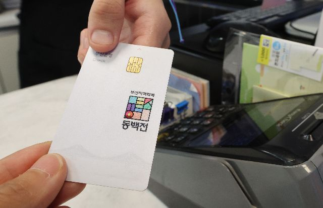 최근 부산 중구청이 지역화폐 동백전 추가 적립금을 자체 예산으로 지급하기로 하면서 일선 구·군에서 동백전 인프라 활용도를 높여야 한다는 목소리가 나온다. 사진은 지난해 7월 부산 동구의 한 가게에서 한 시민이 동백전 카드로 결제하는 모습. 부산일보DB