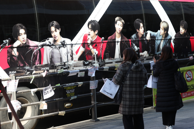 그룹 방탄소년단(BTS)의 광화문 공연을 앞둔 19일 서울 용산구 하이브 인근에서 팬들이 관련 홍보물을 둘러보고 있다. 연합뉴스