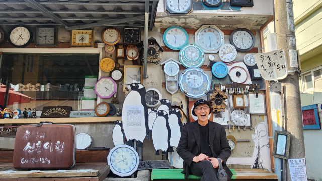 광주 양림동 펭귄마을 촌장 김동균 씨가 가장 애착 가는 펭균마을 내 시계 거리에서 환하게 웃고 있다. 13년 전부터 쓰레기들을 주워 모아 펭균마을을 조성한 김 촌장의 노력으로 이곳은 연간 20만 명이 찾는 명소가 됐다. 김진성 기자 paperk@