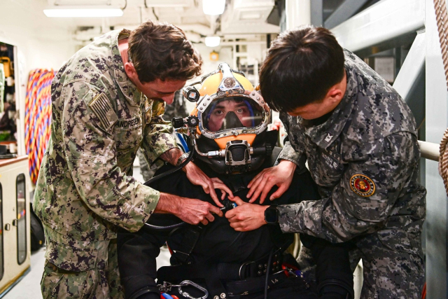 지난 8일 수상함구조함 통영함(ATS-ll·3500t급)에서 진행된 연합 구조전 훈련에서 한국·미국해군 잠수사들이 호주해군 잠수사의 잠수장비 착용을 도와주고 있다. 해군 제공