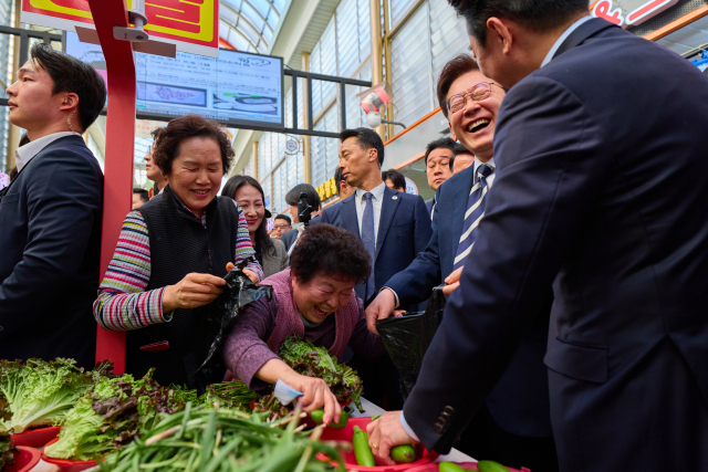 이재명 대통령이 지난달 25일 한국항공우주산업(KAI)에서 열린 KF-21 양산 1호기 출고식에 참석한 뒤 경남 진주시 진주중앙시장을 방문해 상인과 대화를 나누고 있다. 연합뉴스