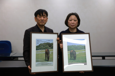 신우철 부경마주협회장과 아내 조춘희 여사가 신 부녀의 마필코노미 액자와 함께 기념촬영을 하고 있다.