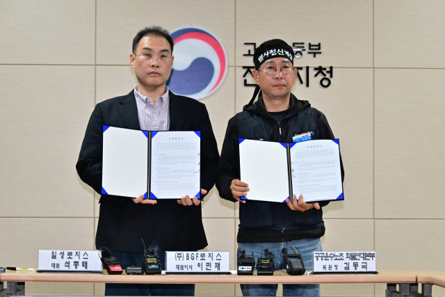 BGF로지스 이민재 대표이사(왼쪽)와 공공운수노조 화물연대본부 김동국 위원장이 단체협약서에 서명한 뒤 협약서를 들어보이고 있다. 김현우 기자