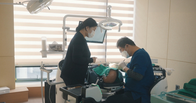 오른쪽 아래 어금니 3개를 원데이 임플란트로 시술받은 스티븐 오 감독이 “시술 후 2년이 경과한 현재도 좋은 컨디션을 유지하고 있다”며 만족감을 표했다. 사진은 하버드센트럴치과에서 정동수 원장이 스티븐 오 감독에게 임플란트 시술을 하고 있는 장면. 하버드센트럴치과 제공