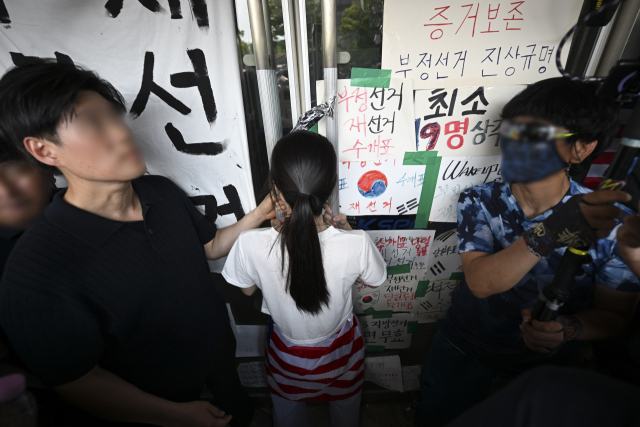 6·3 지방선거 투표용지 부족 사태로 시작한 서울 송파구 올림픽공원 핸드볼경기장 일대 '개표소 봉쇄 시위'가 이어지는 가운데 6월 16일 한 시위 참가자가 대한체육회 등 입주 단체 관계자들의 진입을 막아서고 있다. 연합뉴스