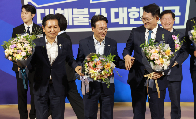 더불어민주당 당 대표 본경선에 진출한 정청래(왼쪽부터), 김민석, 송영길 후보가 23일 국회 의원회관에서 당 대표·최고위원 예비경선 결과 발표 뒤 기념촬영을 위해 손을 잡고 있다. 연합뉴스