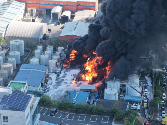 14일 오전 울산 울주군 온산읍 부승화학 공장 화재 현장에서 소방당국이 저장탱크 사이로 번진 불길을 잡기 위해 진화 작업을 벌이고 있다. 공장 바닥이 소방대가 뿌린 거품 소화약제로 하얗게 덮여 있다. 독자 제공