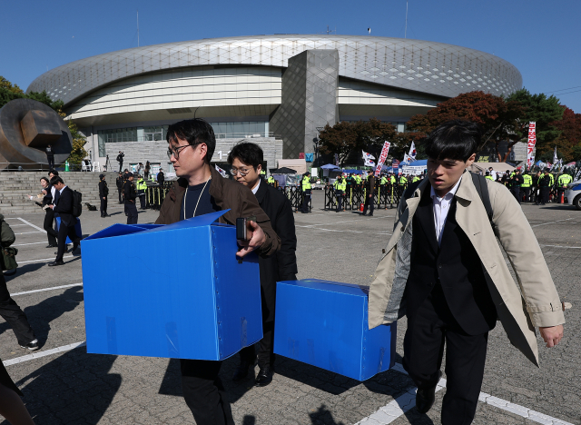 6·3 지방선거 투표용지 부족 사태 등을 수사하는 이태한 선거관리위원회 특별검사팀이 27일 서울 송파구 올림픽공원 핸드볼경기장을 압수수색했다. 특검 관계자들이 이날 상자를 들고 송파지역 개표소로 쓰인 핸드볼경기장을 나서고 있다. 연합뉴스